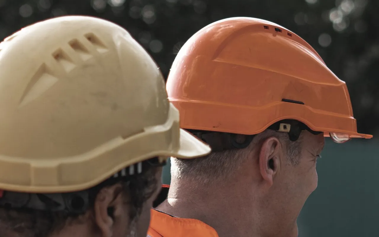 Two workers wearing helmets and high-visibility vests